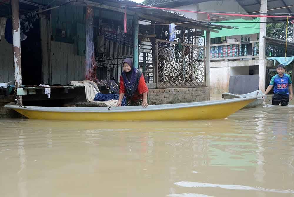 Che Hasnah Awang, 55, menyediakan bot bagi memudahkan beliau membawa anak perempuannya yang juga OKU fizikal berpindah ke PPS berikutan rumahnya di Kampung Kijang setiap tahun terkesan banjir. - Foto Bernama