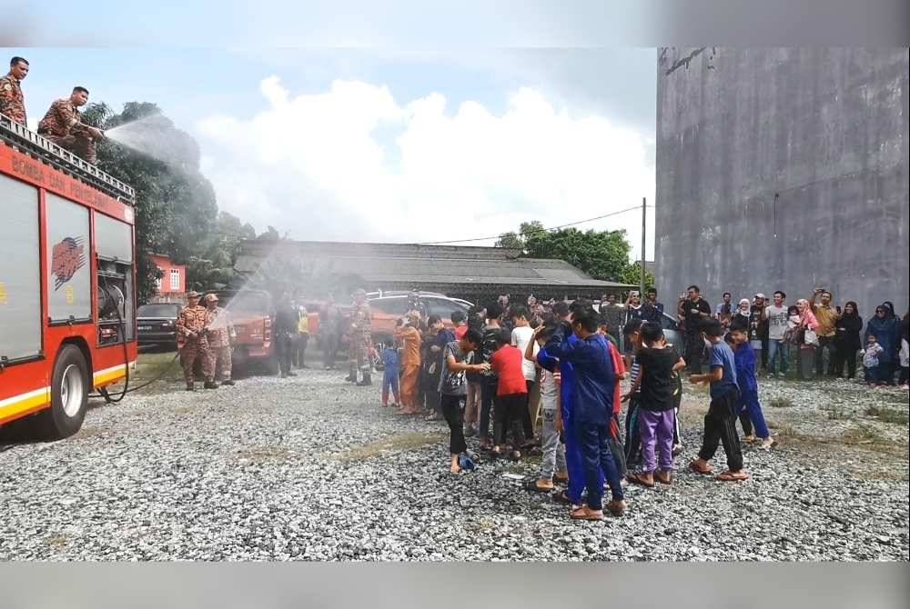 Kanak-kanak 'dimandikan' menggunakan semburan air dari trak bomba pada hari pertama program mega sunathon di Kuala Terengganu.
