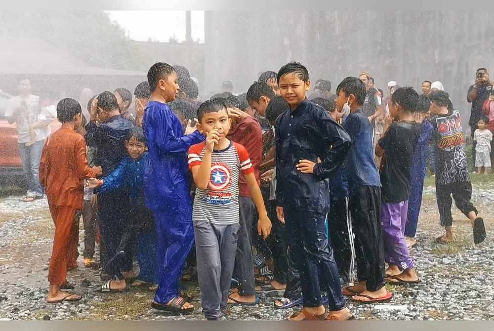 Kesemua kanak-kanak basah lencun setelah 'dimandikan' air semburan dari trak bomba.