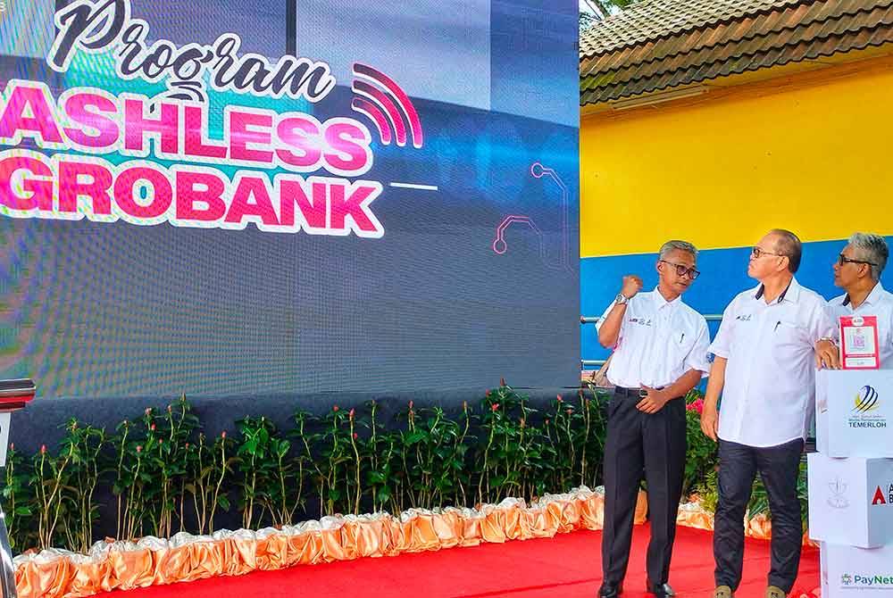 Wan Rosdy (tengah) bersama Suris (Kiri) dan Ahmad Badli ketika menyempurnakan pelancaran Cashless Pekan Sehari Temerloh di Terminal Bas Lurah Semantan di Temerloh pada Ahad.