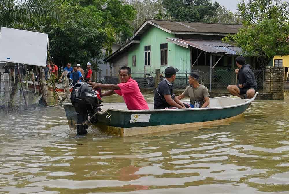 Penduduk menggunakan bot untuk membantu memindahkan penduduk dari Kampung Serongga ke PPS Sekolah Kebangsaan Sri Kiambang berikutan kediaman mereka dilanda banjir. - Foto Bernama