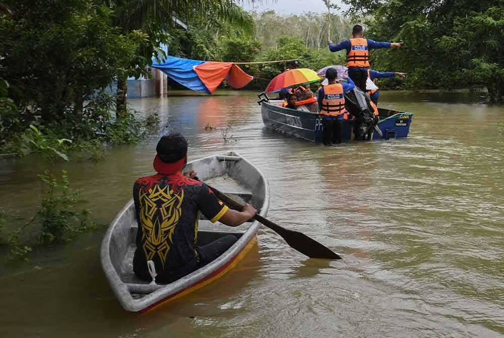 Anggota polis Ibu Pejabat Polis Daerah (IPD) Pasir Mas membantu memindahkan penduduk Kampung Serongga ke PPS Sekolah Kebangsaan Sri Kiambang berikutan kediaman mereka dilanda banjir. - Foto Bernama
