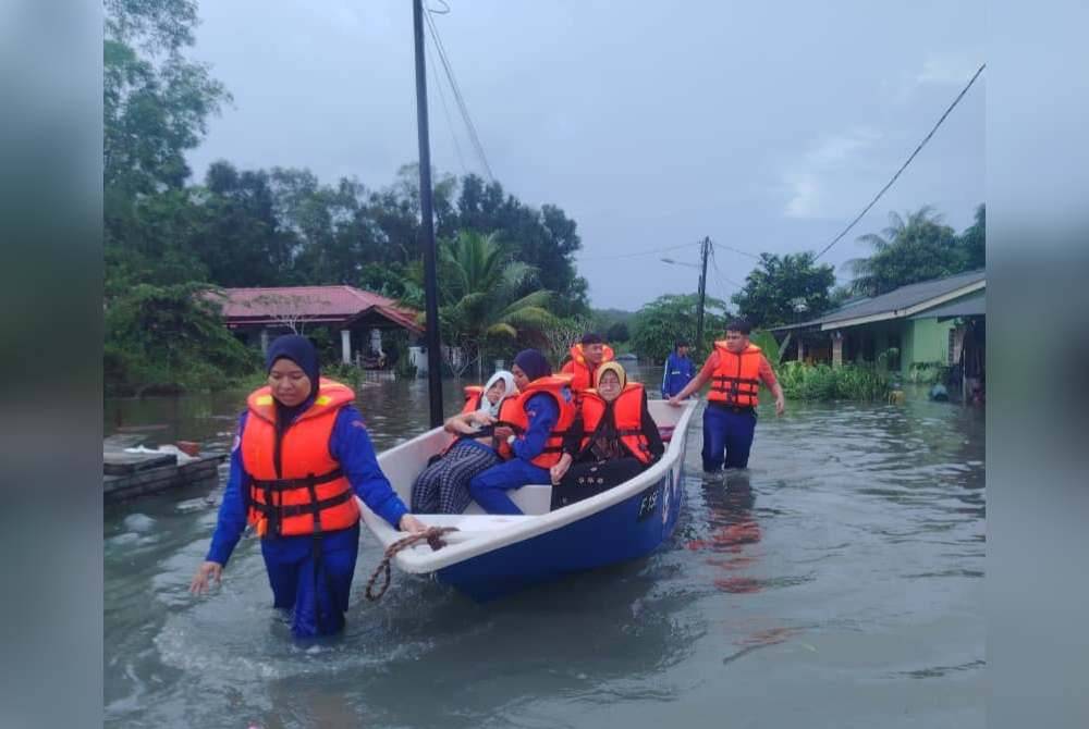 Anggota penyelamat membantu memindahkan penduduk yang terjejas banjir. - Foto APM