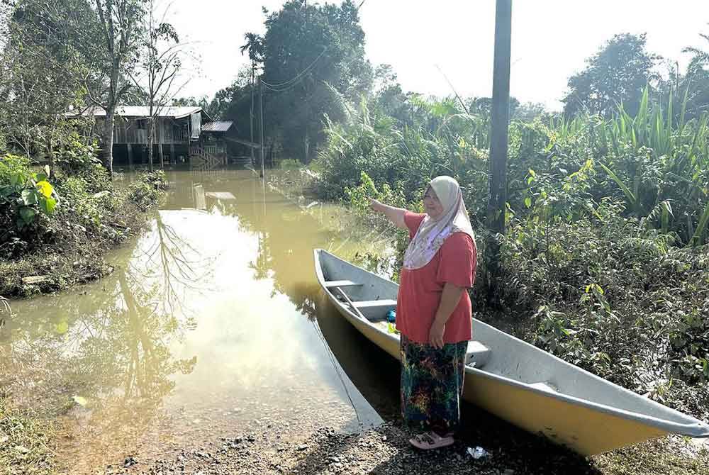 Rosilawati menunjukkan persekitaran rumahnya yang masih ditakungi air.