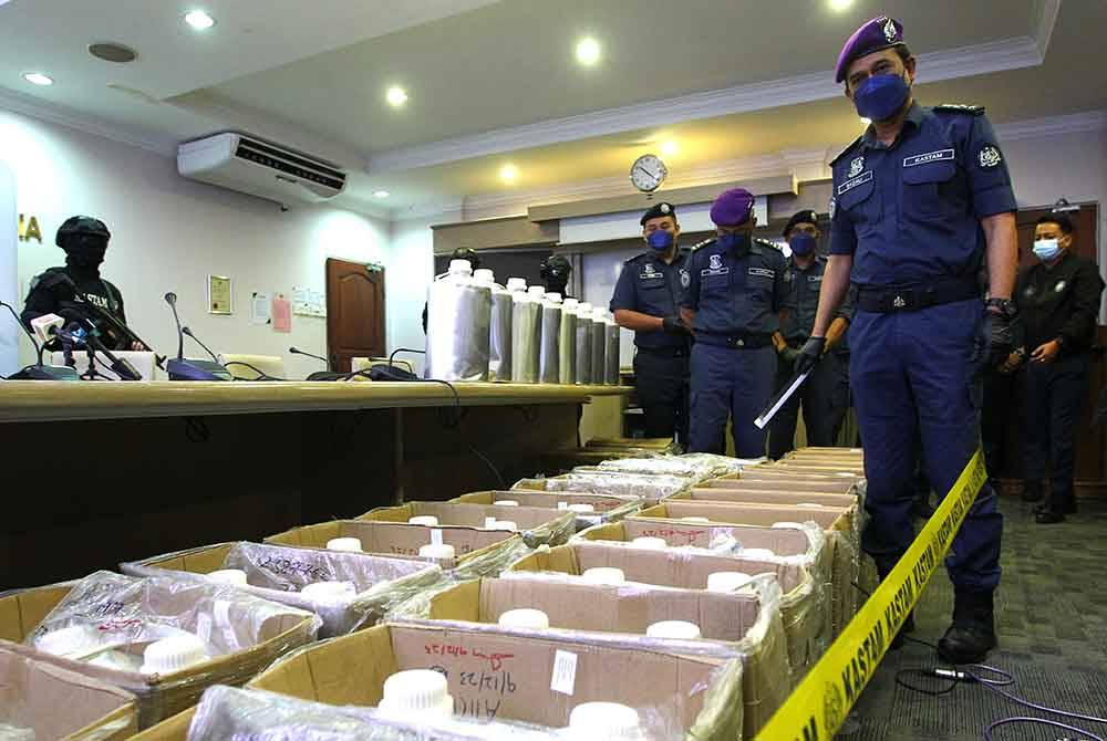 Sazali (depan) menunjukkan botol aluminium berisi dadah jenis Fentanyl yang dirampas