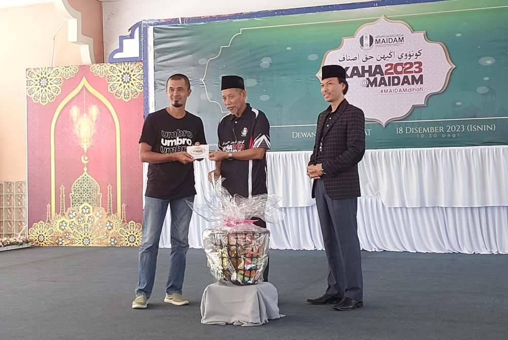 Shaikh Harun (tengah) menyampaikan sumbangan pada salah seorang asnaf.