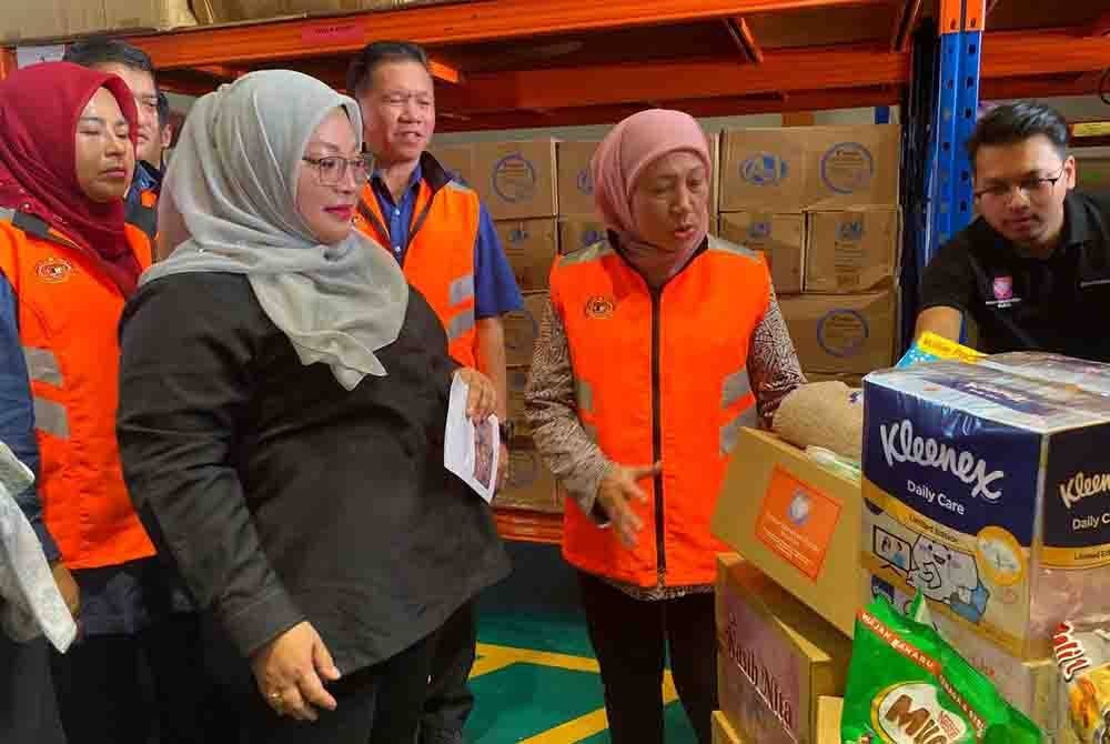 Nancy (dua,kanan) melihat antara bekalan makanan serta keperluan yang akan diagihkan kepada mangsa banjir di PPS.