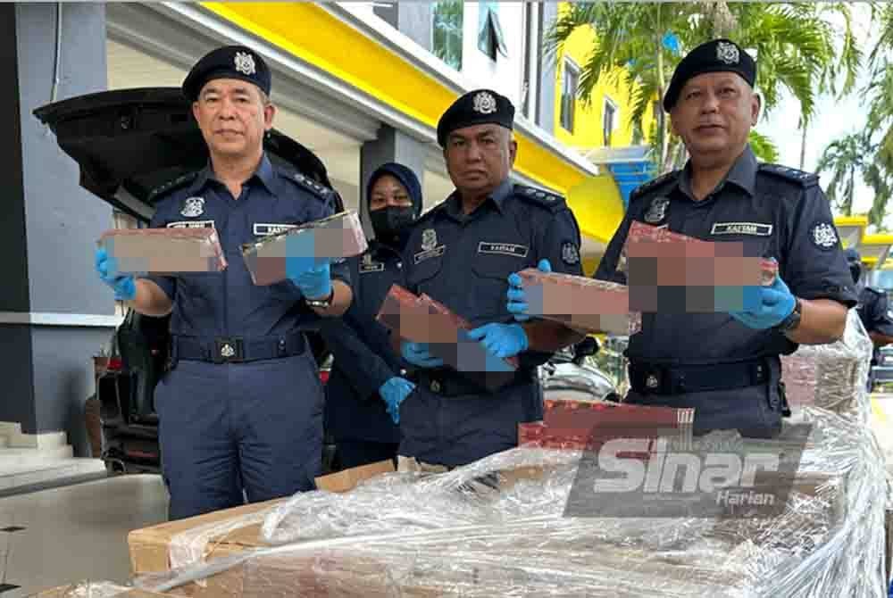 Wan Jamal (kiri) bersama pegawai menunjukkan rokok seludup yang dirampas.