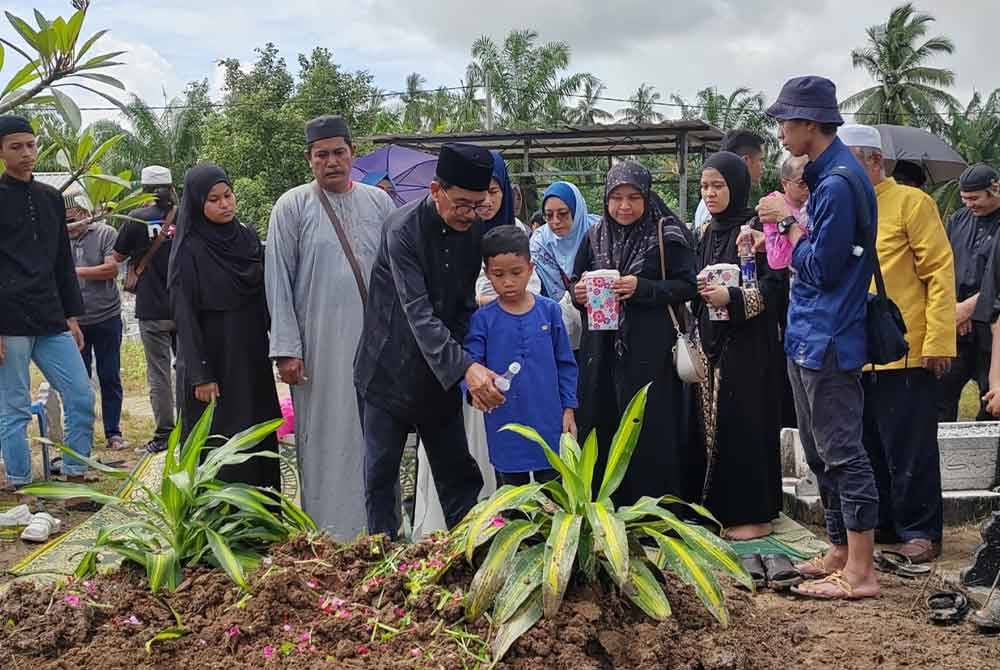 Menantu, Hassan Ahmad, 69, menyiram air di pusara Allahyarham sebaik selesai pengebumian di Tanah Perkuburan Islam Kampung Sungai Balai Baroh, Bagan Datuk jam 2.30 petang pada Selasa.