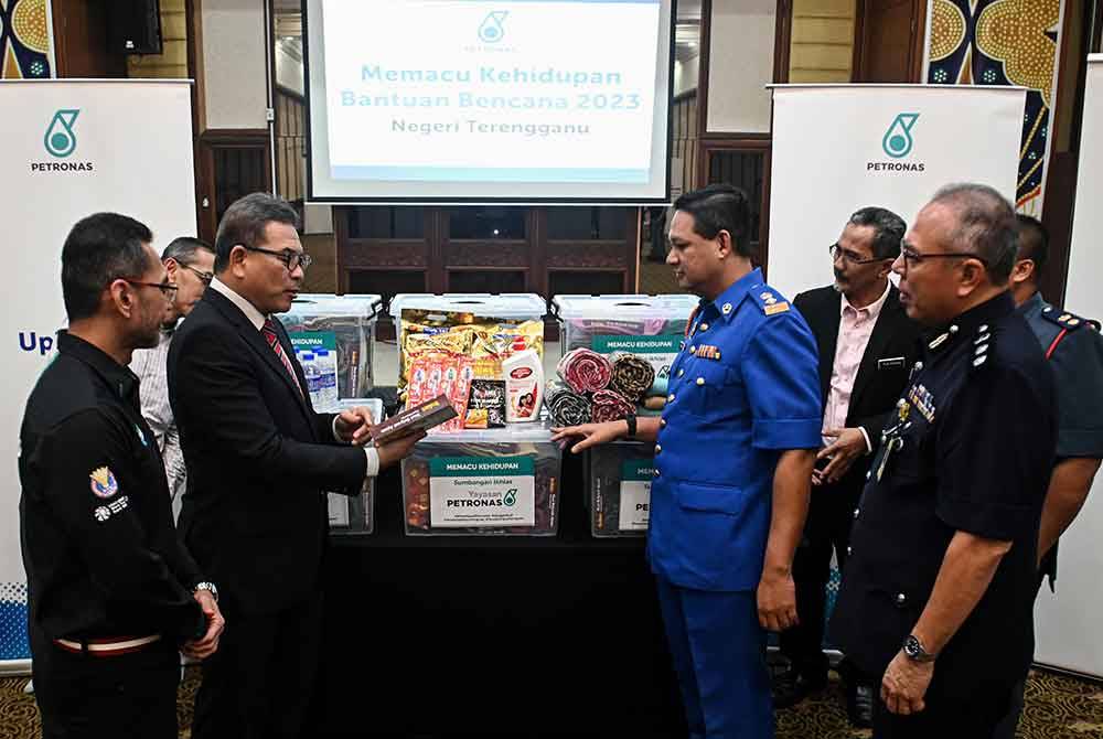 Tengku Farok Hussin (dua dari kiri) Mohammad Ahmad Shazly Ramli (kiri) melihat kit bantuan banjir sempena Program Memacu Kehidupan Bantuan Bencana 2023 di sebuah hotel, pada Selasa. - Foto Bernama