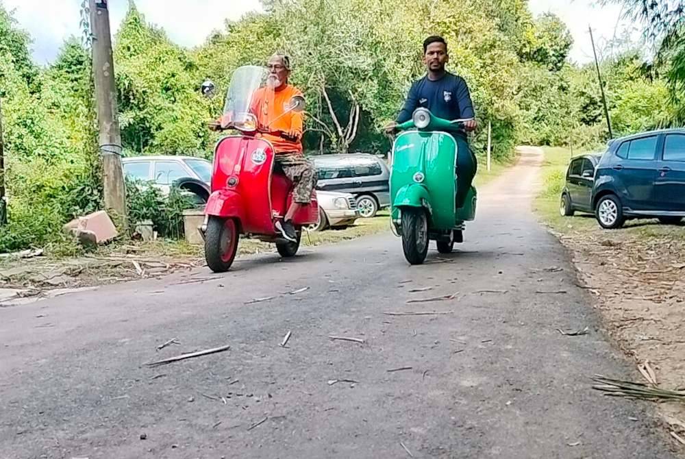 Rahim (kiri) menunggang Vespa miliknya di Kampung Pulau Sebang di sini, pada Rabu sebagai persiapan ke kembara Kemboja.