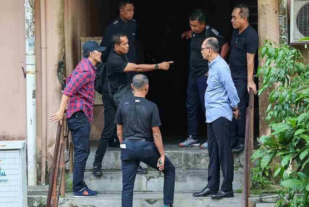 Mohd Shuhaily (dua, kiri) bersama anggota polis tiba di pekarangan Apartmen Idaman, Damansara Damai pada Rabu. - Foto Bernama