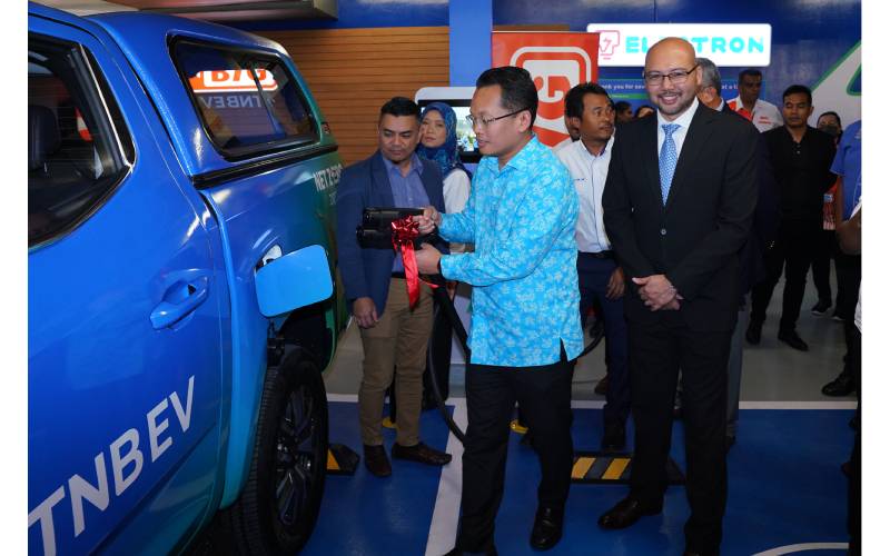 Nik Nazmi mencuba kemudahan stesen pengecasan EV yang disediakan di AEON BiG Wangsa Maju sambil disaksikan Sheikh Farouk (kanan).