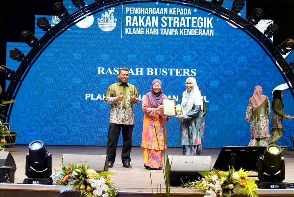 Pasukan Rasuah Buster turut menerima penghargaan disampaikan Noraini (tengah) kepada Pengurus Perhubungan Strategik Rasuah Busters, Wan Normi Hasan (kanan).