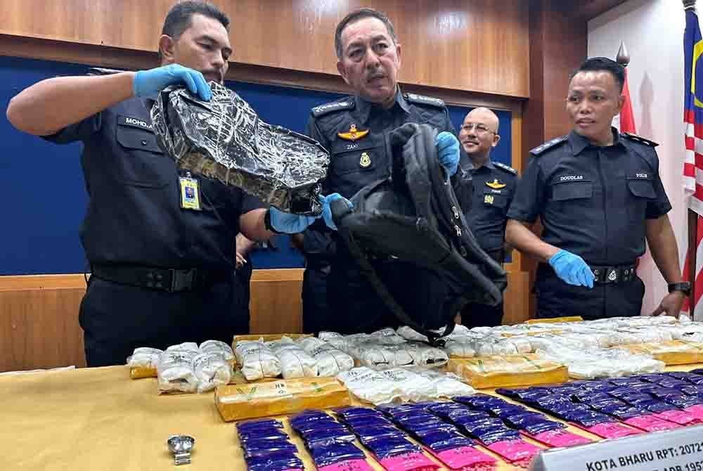 Muhamad Zaki (tengah) menunjukkan beg galas yang dibawa oleh suspek.