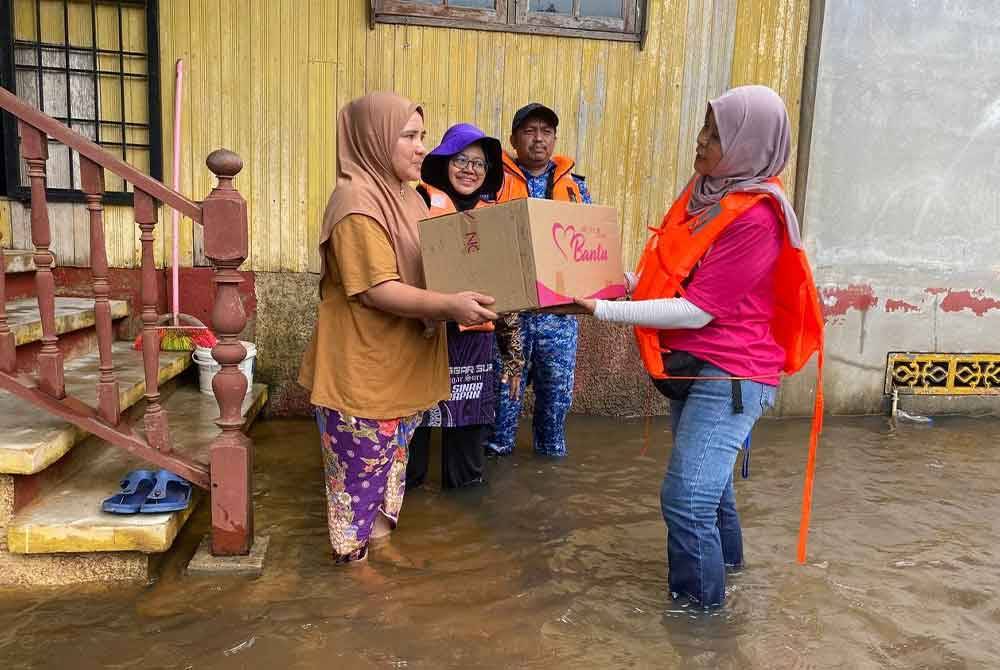Norlaili (dua dari kiri) bersama Yayasan AEON Malaysia, Yayasan Foodbank Malaysia serta Agkatan Pertahanan Awam Malaysia (APM) Rantau Panjang menyampaikan sumbangan kepada penduduk yang terkesan dengan banjir termenung.