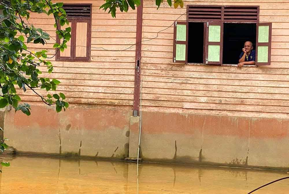 Seorang penduduk di Kampung Bakat, Rantau Panjang hanya mampu termenung melihat keadaan rumah yang terkesan dengan banjir termenung.