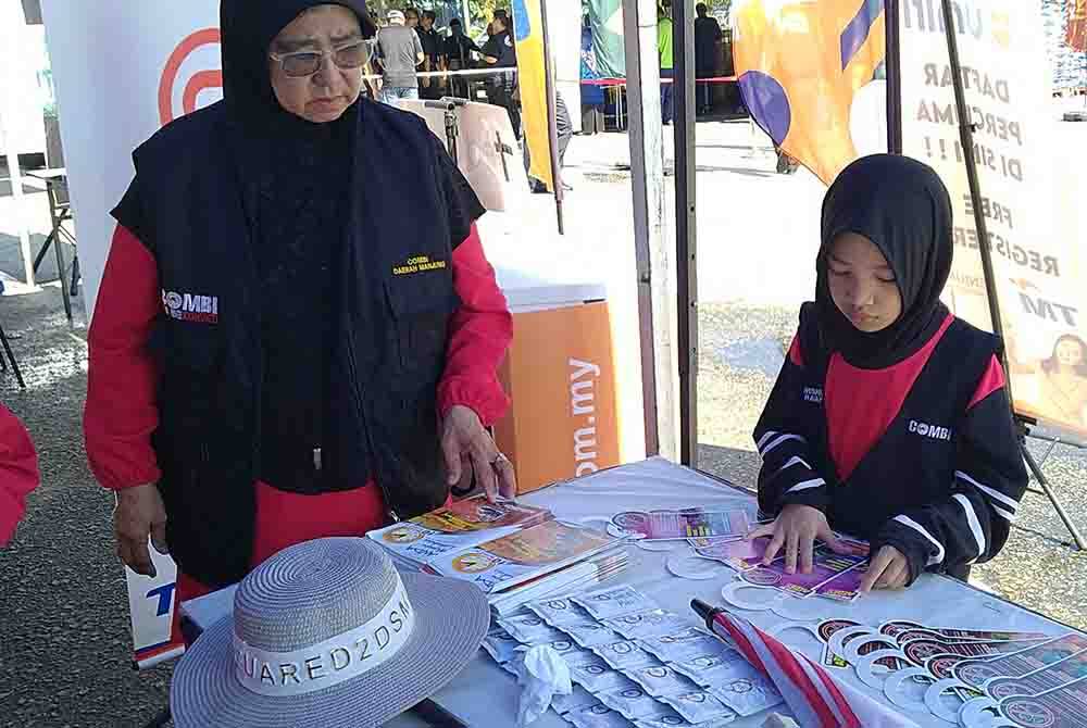 Nur Sania (kanan) memanfaatkan cuti sekolah dengan menyertai kempen cegah denggi bersama Combi Daerah Manjung.