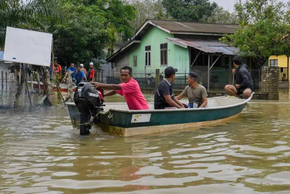 Penduduk menggunakan bot untuk membantu memindahkan penduduk dari Kampung Serongga ke Pusat Pemindahan Sementara (PPS) Sekolah Kebangsaan Sri Kiambang berikutan kediaman mereka dilanda banjir ketika tinjauan pada 17 Disember lalu. - Foto Bernama