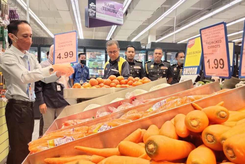 Azman (tengah) melihat sayur-sayuran di bawah harga kawalan Pemantauan Skim Harga Maksimum Musim Perayaan (SHMMP) di sini pada Sabtu.
