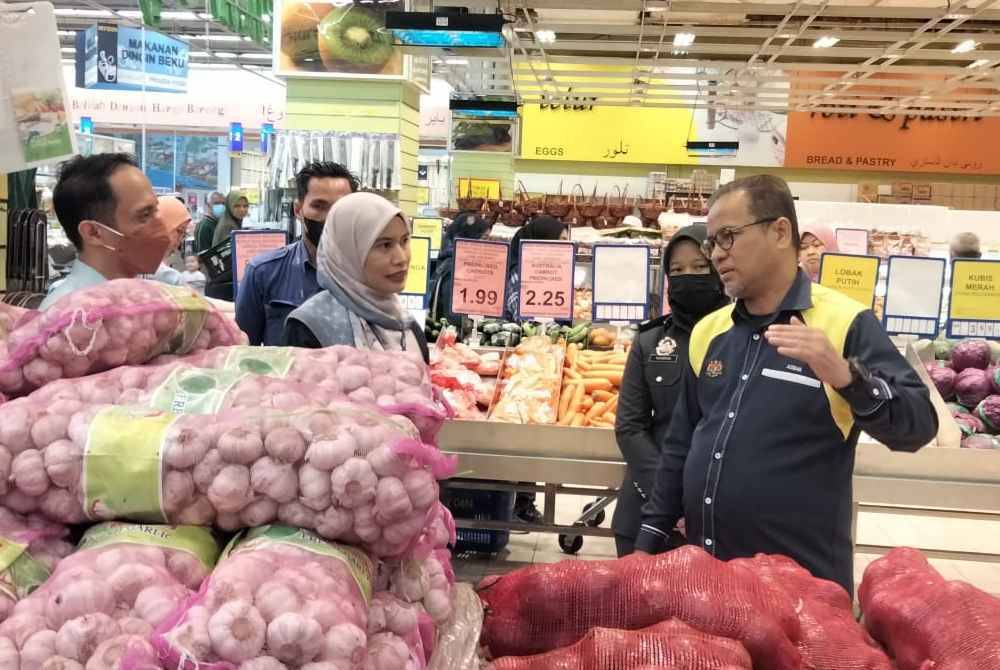 Azman (kanan) memantau harga bawang merah besar Pemantauan Skim Harga Maksimum Musim Perayaan (SHMMP) di sini pada Sabtu.