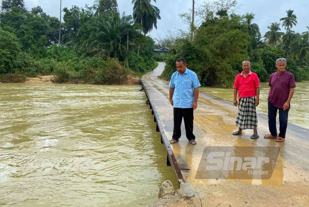 Mat Jusoh (kiri) bersama penduduk menunjukkan jambatan Sungai Pasir Jering yang telah siap dibaiki selepas hampir seminggu runtuh akibat banjir.