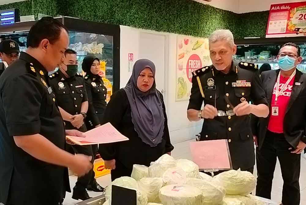 Lilis Saslinda (tengah) meninjau harga barang kawalan musim perayaan Krismas di sebuah pasar raya di Austin Heights pada Sabtu.