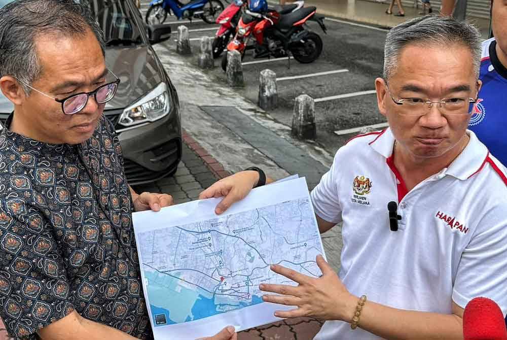 Cher Leong (kiri) dan Poay Tiong (dua dari kiri) menunjukkan peta jalan-jalan yang ditutup susulan penutupan jalan selama 54 jam di Banda Hilir.