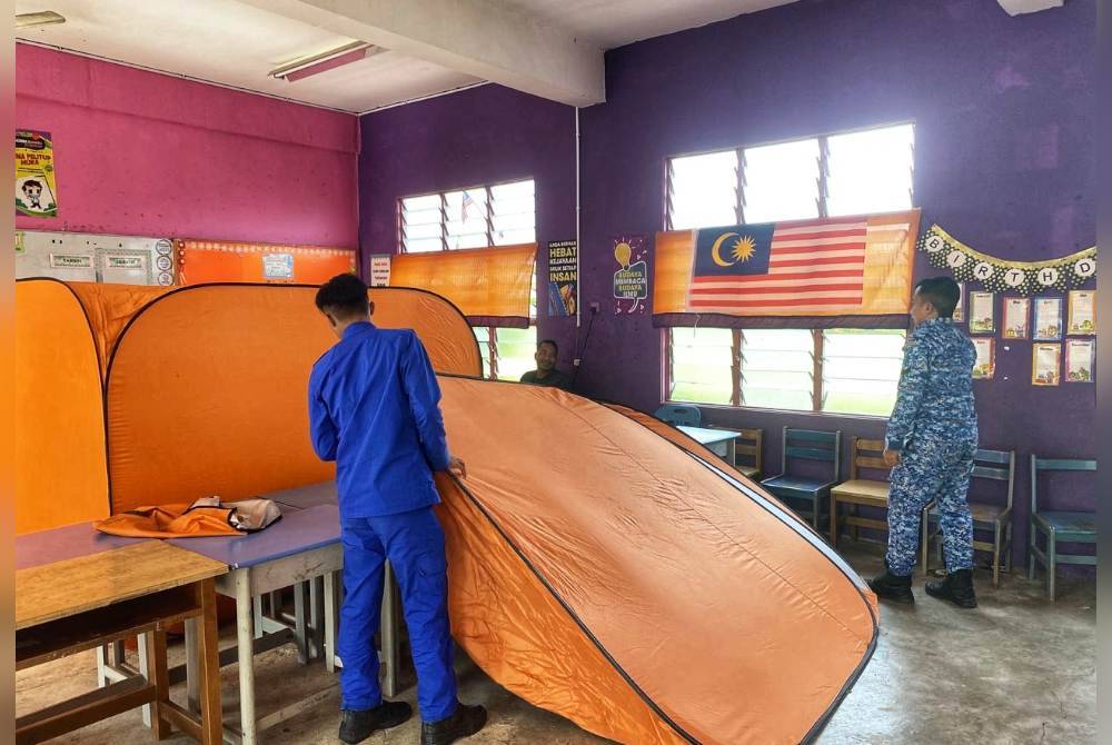 Anggota APM membantu memasang khemah yang menempatkan mangsa banjir di PPS tersebut. - Foto Ihsan APM