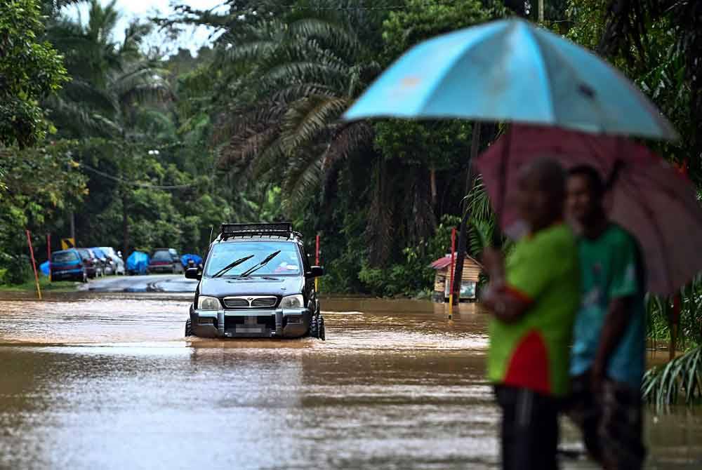 Sebuah kenderaan meredah banjir selepas kawasan berkenaan dinaiki air ketika tinjauan di Kampung Kepah hari ini. - Foto: Bernama