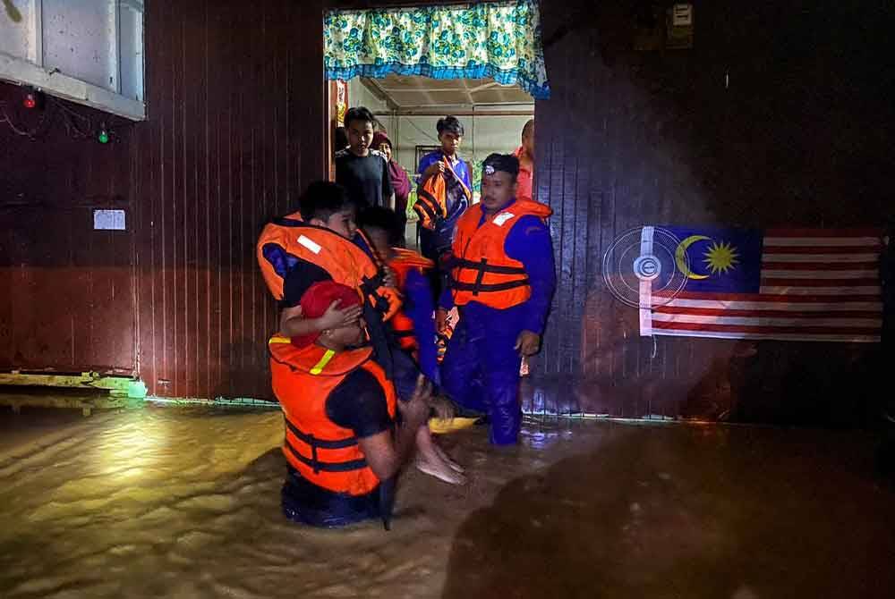 Anggota APM membantu memindahkan mangsa banjir di Raub. - Foto ihsan APM