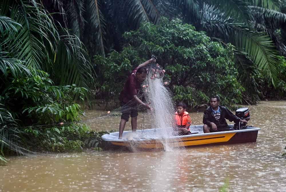 Penduduk tidak melepaskan peluang memasang pukat selepas kawasan berkenaan dinaiki air ketika tinjauan di Kampung Kepah. - Foto Bernama