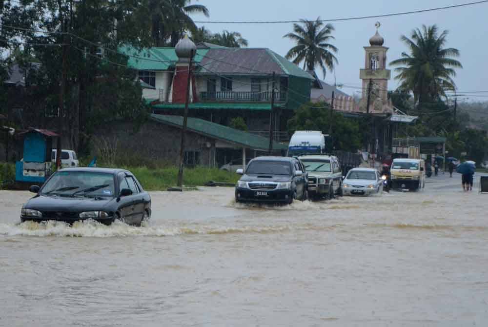 Pengguna jalan raya meredah air yang melimpahi Jalan Jedok-Jeli di Kampung Kelewek. - Foto Bernama