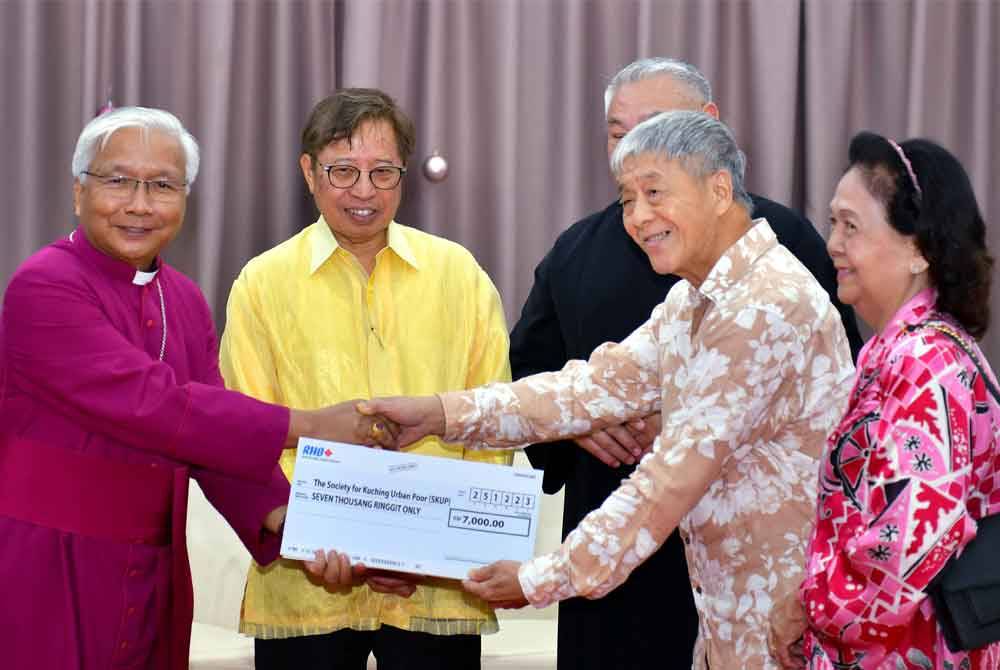 Abang Johari (dua dari kiri) memerhatikan penyerahan cek bantuan kepada Komuniti untuk Golongan Miskin Bandar Kuching (SKUP) pada majlis Rumah Terbuka Krismas Bishop Kuching di Gereja Besar St Thomas, pada Isnin. - Foto Bernama