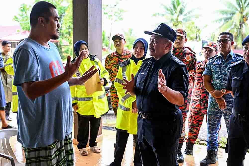 Wan Rukman (kanan) beramah mesra bersama mangsa banjir. Foto Bernama