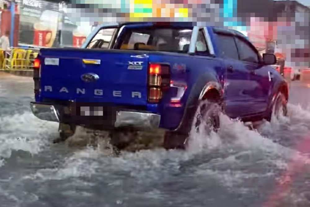 Sebuah kenderaan meredah banjir akibat hujan lebat dan fenomena air pasang besar di Jalan Persekutuan di Tanjong Karang menghala ke Sekinchan pada Selasa.