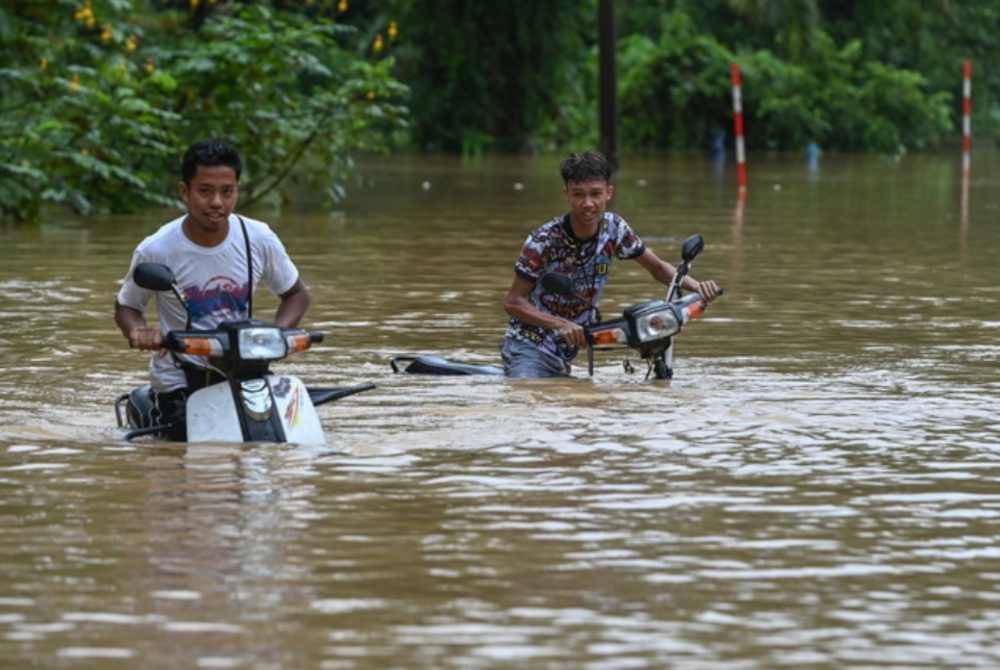 Penduduk meredah banjir dengan menaiki motosikal ketika tinjauan di Kampung Pengkalan Ajal pada 14 Disember lalu.