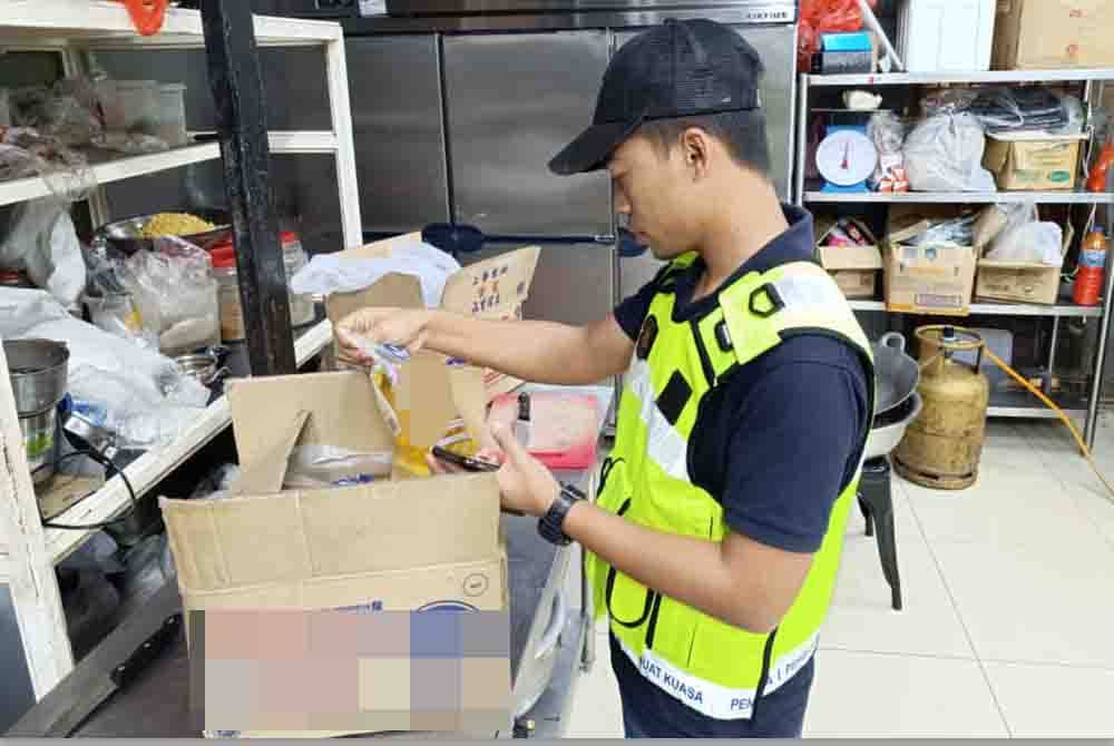 Seorang anggota KPDN Kuala Lumpur memeriksa minyak masak yang disimpan pemilik restoran berkonsepkan Asia Selatan yang diserbu KPDN Kuala Lumpur di Jalan Ipoh, dekat sini baru-baru ini.