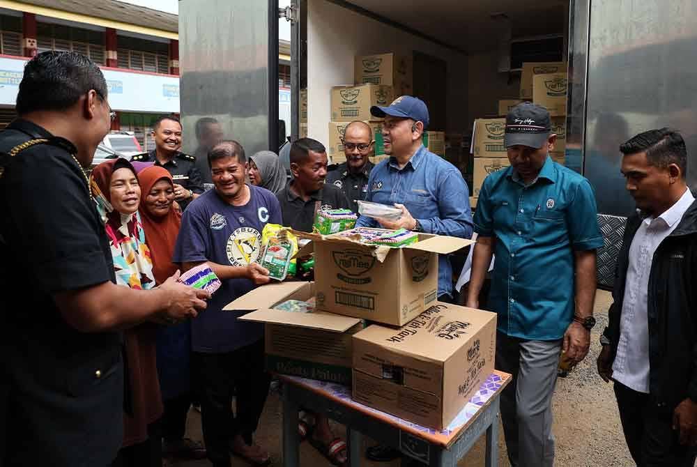 Saharuddin (tiga dari kanan) menyerahkan sumbangan makanan daripada Sekretariat Food Bank Malaysia kepada mangsa banjir di PPS Sekolah Menengah Kebangsaan Menerong, Ajil, hari ini. - Foto Bernama