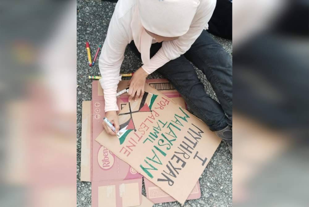 Peserta menulis plakad menyatakan sokongan terhadap Palestin.