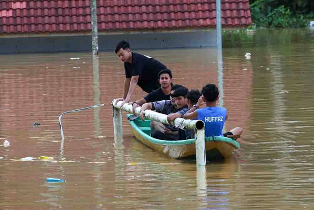 Penduduk kampung melihat paras air sekitar Kampung Manek Urai yang dilanda banjir susulan limpahan air Sungai Lebir. - Foto Bernama