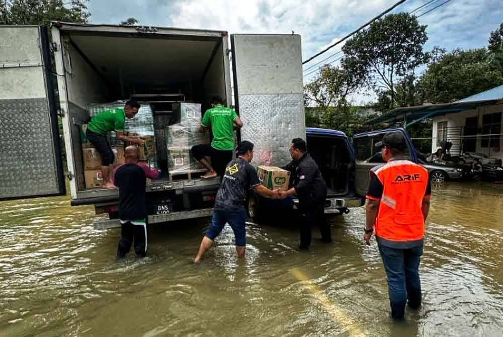 Pekerja pasar raya Econsave sedang mengangkut barangan untuk diagihkan kepada mangsa banjir.