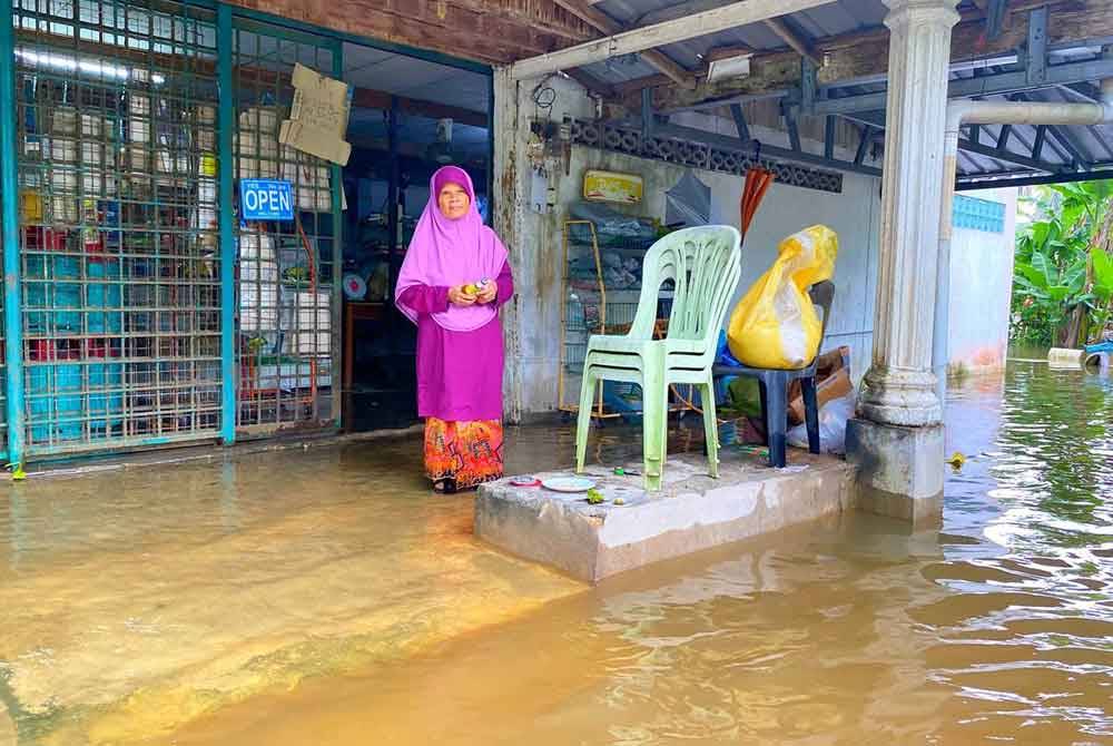 Walaupun air sudah melimpah masuk ke kedai runcit milik Fatimah, namun dia masih meneruskan operasi.