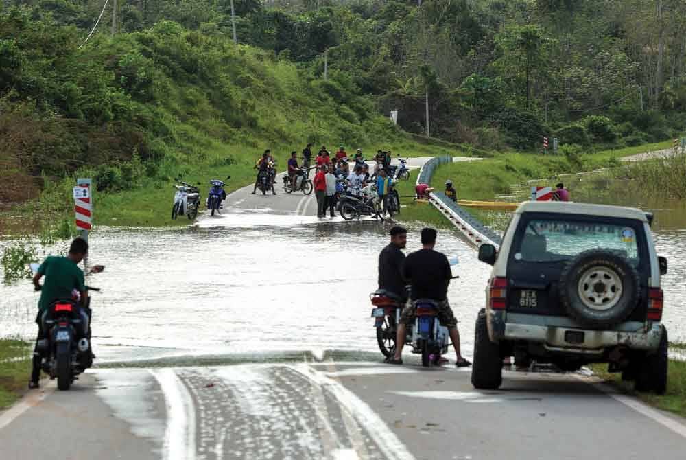 Penduduk kampung yang terputus hubungan terpaksa menggunakan sampan untuk menyeberangi air banjir di Jalan Kampung Pemberian susulan limpahan air Sungai Lebir. - Foto Bernama
