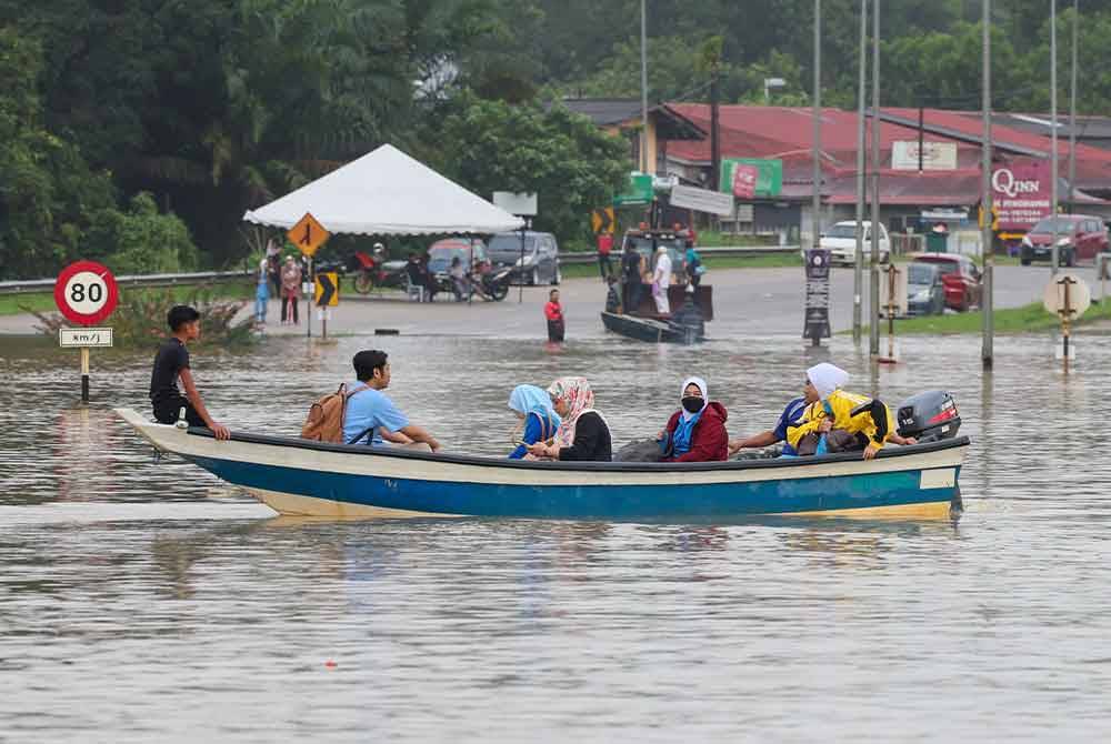 Kakitangan Hospital Hulu Terengganu menaiki bot untuk ke hospital selepas jalan utama Ajil- Kuala Berang terputus berikutan banjir semasa tinjauan hari ini. - Foto Bernama