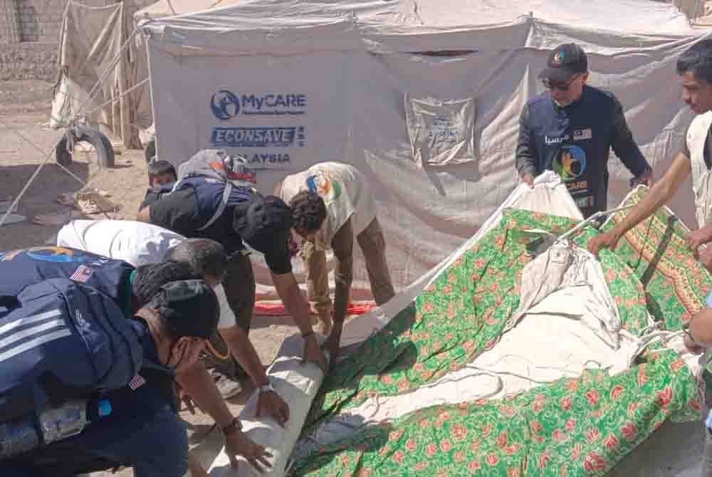 Dr Mohd Zin (tengah) bersama sukarelawan memasang khemah baharu menggantikan yang lama untuk mangsa perang hasil sumbangan rakyat Malaysia.