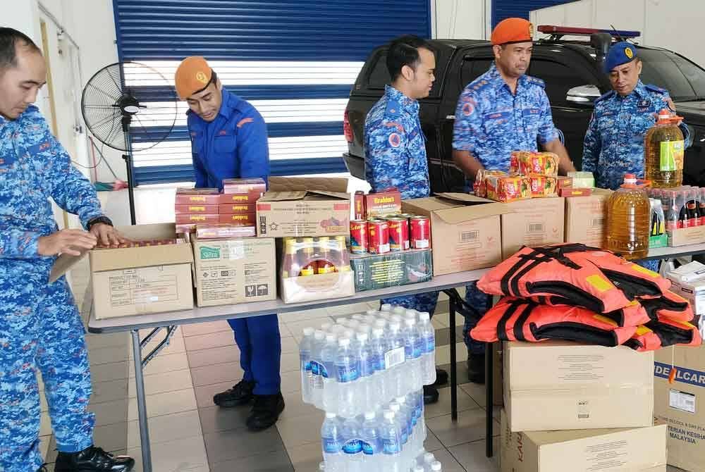 Che Adam (dua dari kanan) bersama barangan sumbangan pelbagai pihak yang dikumpulkan di Pusat Pengumpulan Barangan Sumbangan Bencana Pantai Timur di Pejabat APM Pahang.