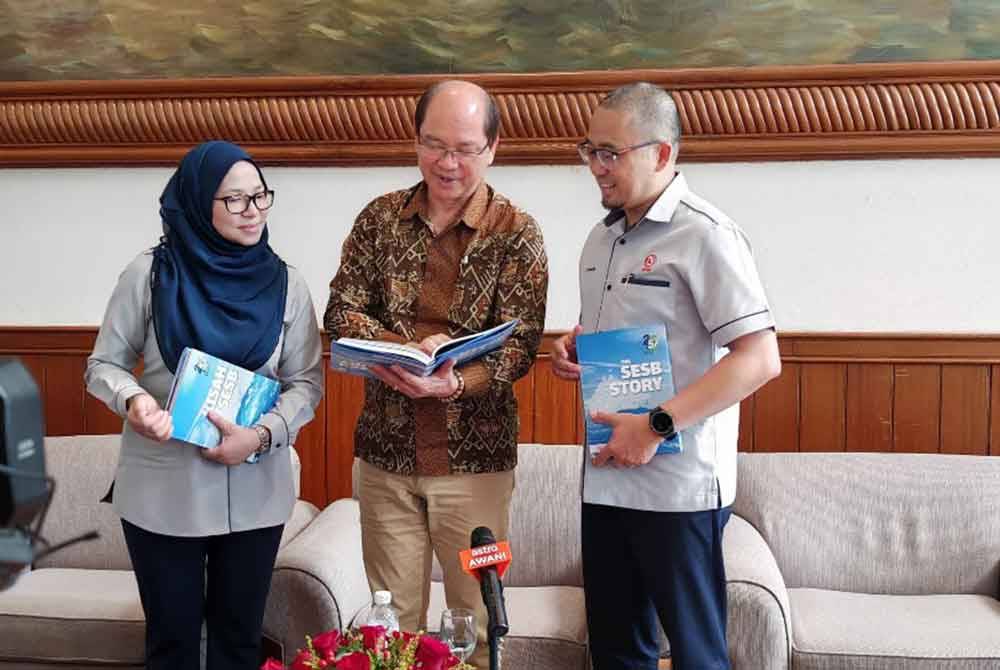 Madius menunjukkan buku The SESB Story - Kisah SESB selepas melancarkannya di Kota Kinabalu.
