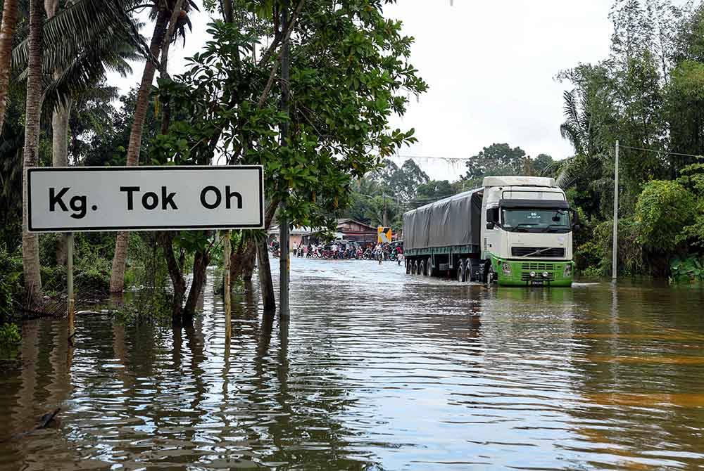 Jalan raya di Kampung Tok Oh dinaiki air dan hanya boleh dilalui kenderaan pacuan empat roda dan kenderaan berat akibat banjir di sekitar kawasan Tumpat. Foto Bernama