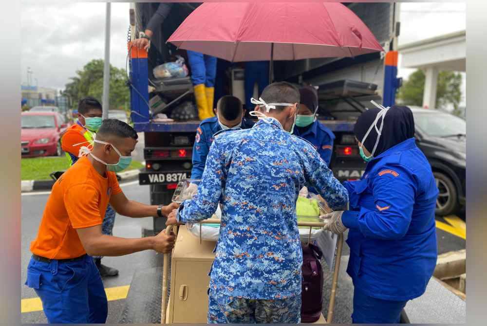 Anggota penyelamat membantu memindahkan penduduk yang terjejas banjir. Foto APM
